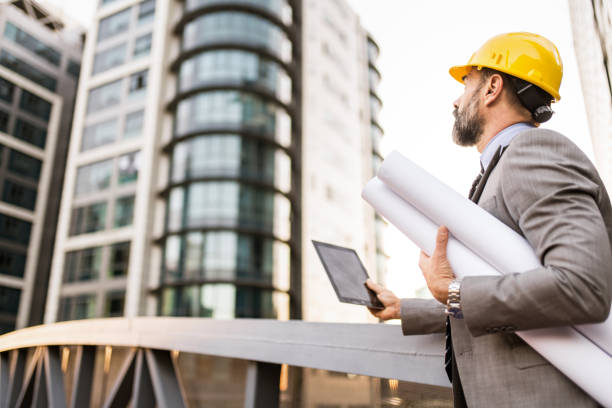 istock Mid adult architect using digital tablet and examining a blueprint at financial district. 1335743293