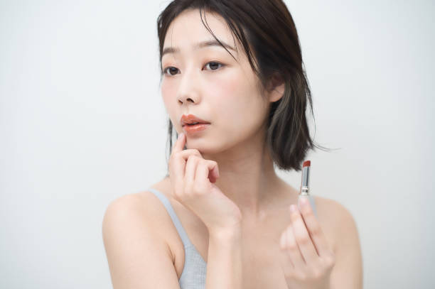 istock Young woman applying lipstick to her lips 1335743327