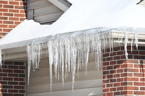 Row of icicles from the roof of a brick house.