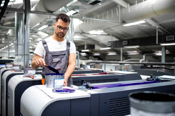 istock Printing machine operator preparing paint for print process in printing house. 1335757419