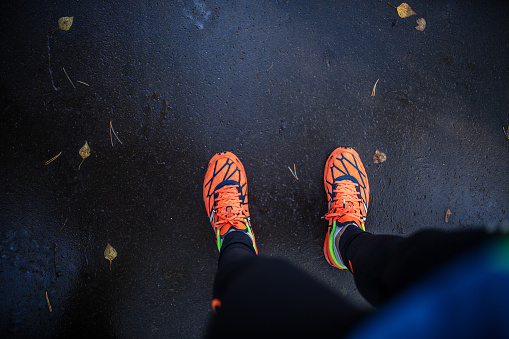 Get ready for jogging. Directly above view of a bright orange sneakers and asphalt road.