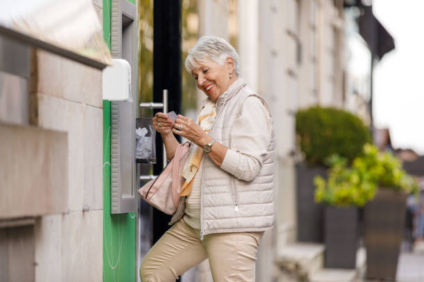 istock An Older Woman is Withdrawing a Cash from ATM Machine. 1335761908