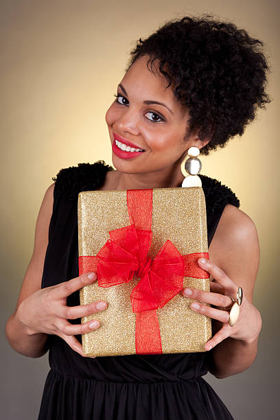 istock Young beautiful African American woman holding a gift 133576548