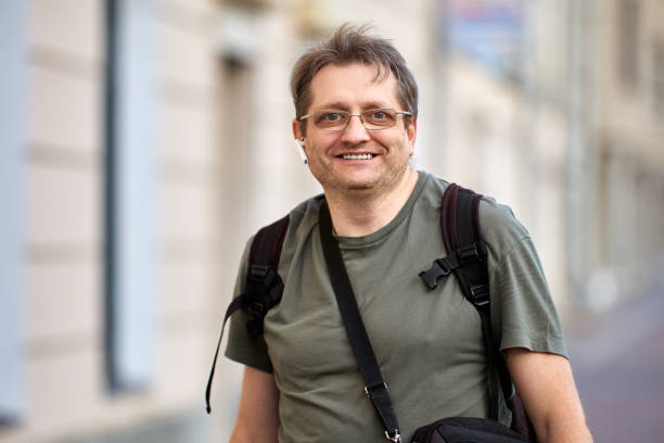istock Happy middle aged man with headset and backpack outdoors. 1335771095