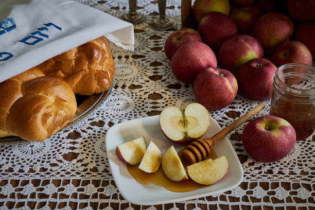 a photograph of a rosh hashanah holiday table with apples, honey and challah bread - rosh hashanah stok fotoğraflar ve resimler