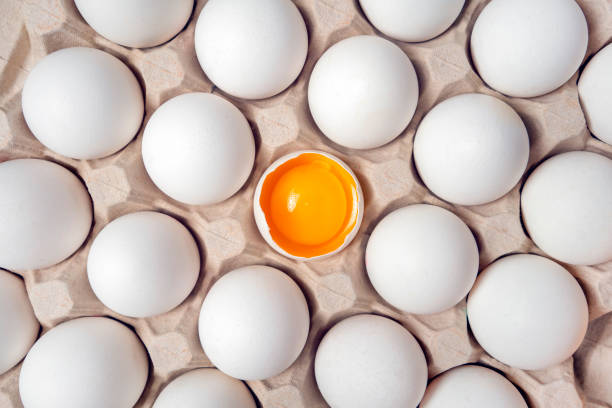 istock Cardboard tray with white eggs. One broken egg in carton box 1335774472