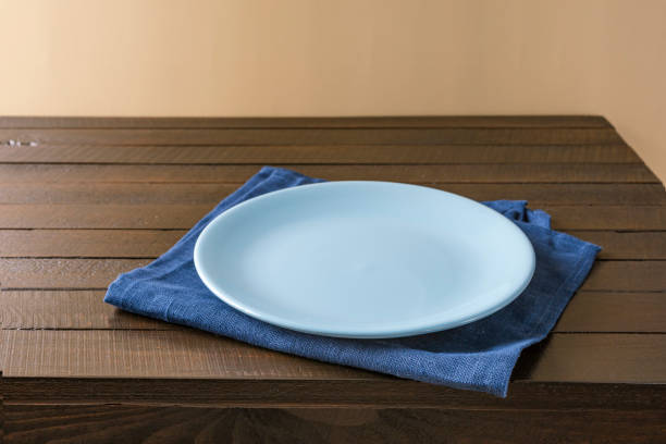 istock Empty plate on napkin on wooden table over grunge blue background. 1335779345