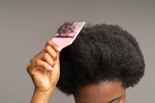 Mujer afroamericana peinando el pelo rizado. Cepillo de pelo de mano femenino étnico en el peinado afro ondulado photo
