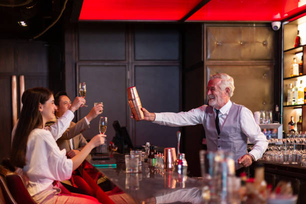 바에서 일하는 동안 고객에게 맥주 나 와인이있는 머그잔을 주는 쾌활한 수석 남성 바텐더. 사람, 알코올 개념 - pub friendship adult party 뉴스 사진 이미지