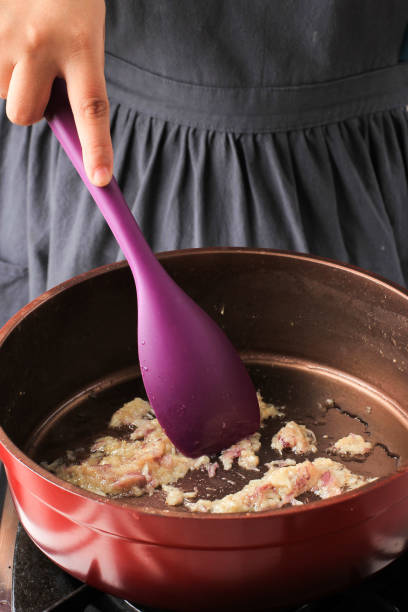 Boiled Asian Egg Yellow Noodle Female Asian Chef Cooking Garlic and Red Onion with Oil in a Pan cooking with garlic stock pictures, royalty-free photos & images