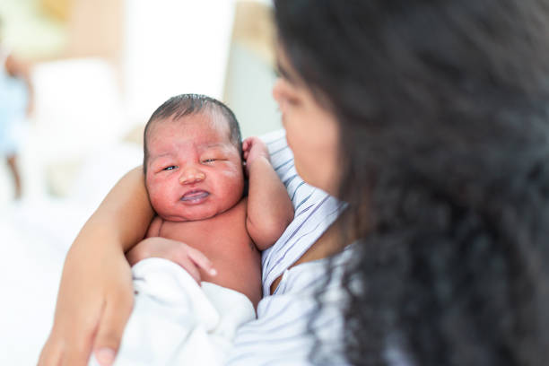 афроамериканская мама вынашивает своего новорожденного ребенка дома. счастливая мама держит на руках младенца. мать обнимает своего новор - new childbirth new life love стоковые фото и изображения