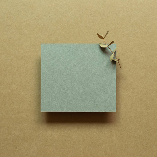 istock Green blank memo paper with eucalyptus leaf on brown background. top view, copy space 1335800514