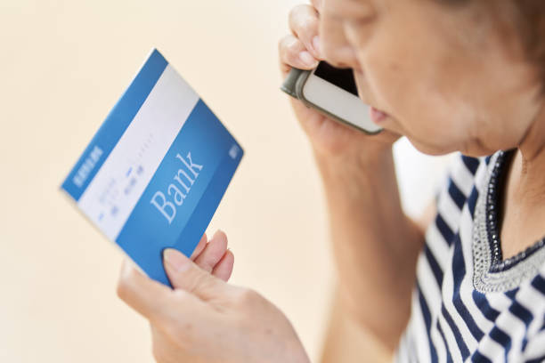 les personnes âgées qui font des appels téléphoniques en regardant leurs livrets - bank statement finance expenses bank account photos et images de collection