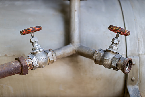 close up of two old water pipes with red round faucets