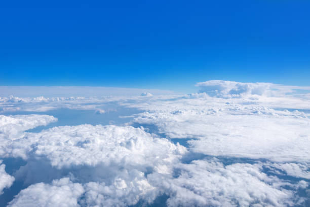 istock Top view from the airplane window on beautiful cumulus fluffy white clouds on a blue sky with a bright sun. 1335809087