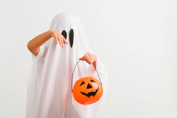 istock child with white dressed costume halloween ghost scary he holding orange pumpkin ghost on hand 1335810497