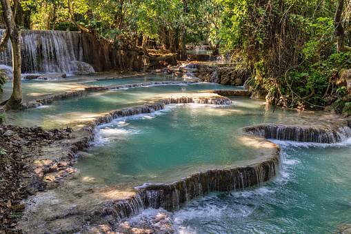 Laos Kuang Si Waterfalls. Cascading natural water pools at the Kuang Si Waterfalls. The Kuang Si Falls, sometimes spelled Kuang Xi or known as Tat Kuang Si Waterfalls, is a three leveled waterfall about 29 kilometers south of Luang Prabang. Cascades of water make the Kuang Si one of Luang Prabang\