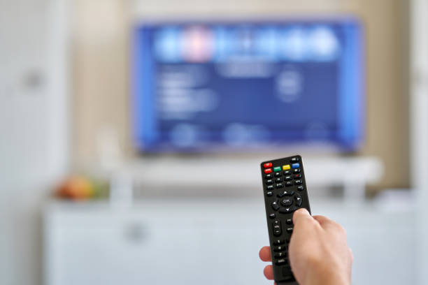 istock Young man holding remote control in hand while watching TV at home 1335827674