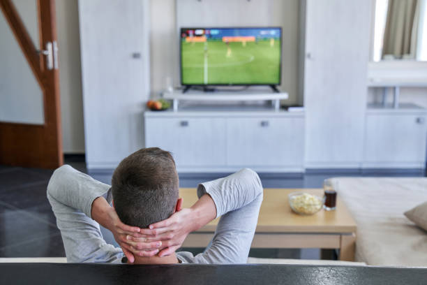 istock Young man watching football match at home 1335827996