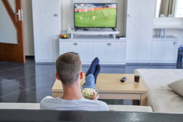 istock Young man watching football match at home 1335827997