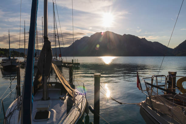 Sailboat on Attersee with Austria Alps at sunrise. Tranquil, yacht sport background Sailboat on Attersee with Austria Alps at sunrise. Tranquil, yacht sport background attersee stock pictures, royalty-free photos & images
