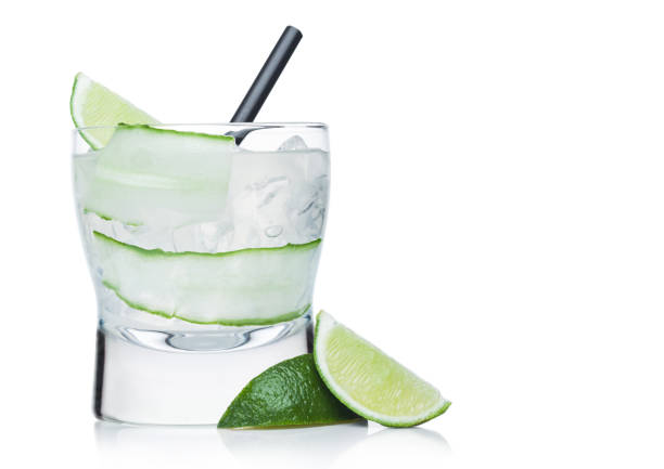 Gimlet cocktail in modern glass with ice cubes and straw, cucumber and lime slice on white. Gimlet cocktail in modern glass with ice cubes and straw, cucumber and lime slice on white background with limes on the side. Space for text Gin stock pictures, royalty-free photos & images