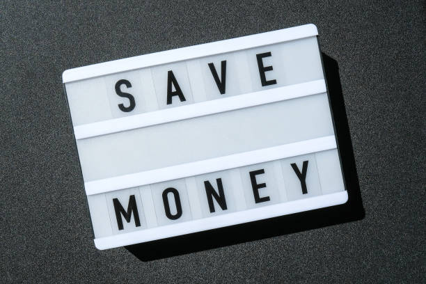 istock Lightbox board on a black background with the words SAVE MONEY in black letters 1335846087