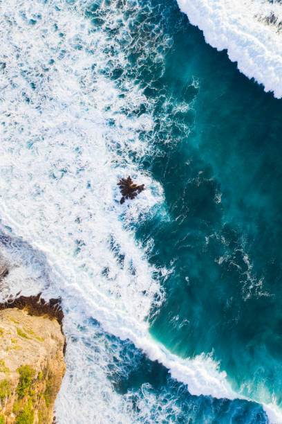 istock Ocean waves hitting a rocky beach and cliffs. View from above. 1335848252