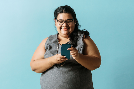 Oversized latinx business woman using a mobile phone. technology concept.