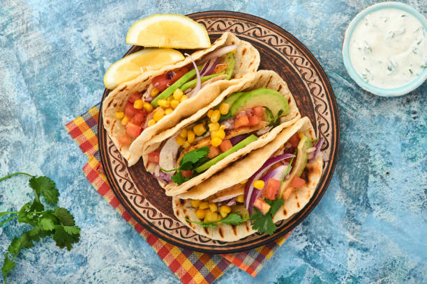 istock Mexican tacos with grilled chicken, avocado, corn kernels, tomato, onion, cilantro and salsa at blue stone table. Traditional Mexican and Latin american street food. Top view. 1335855548
