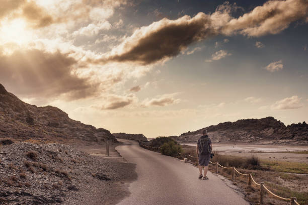istock Tourist with backpack and photo camera walks along a path at sunset. 1335857650