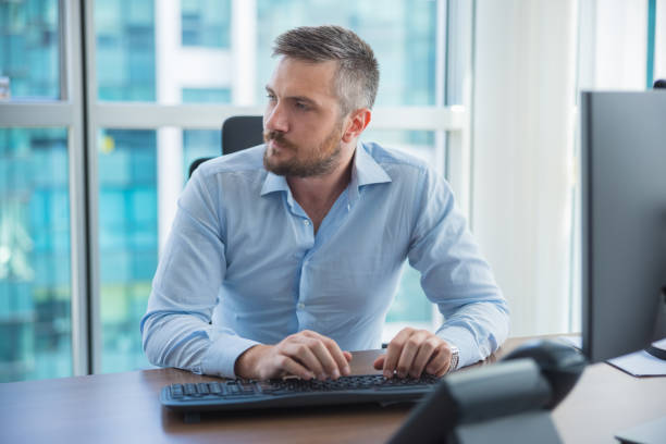 istock Businessman thinking and composing an e-mail at his desk 1335861228
