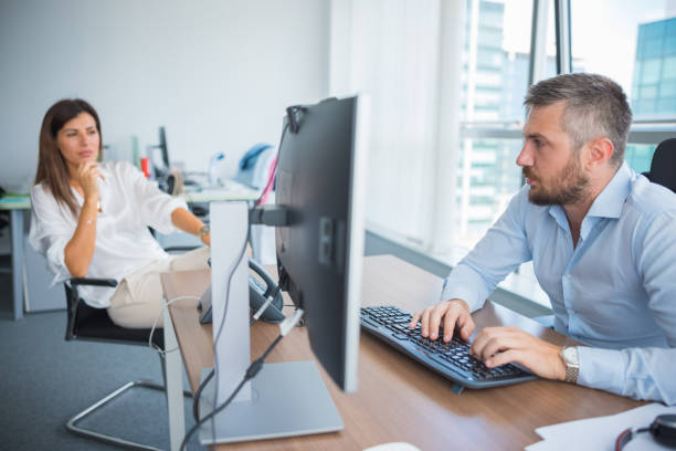 istock Businessman composing an e-mail with his coworker in the office 1335861264