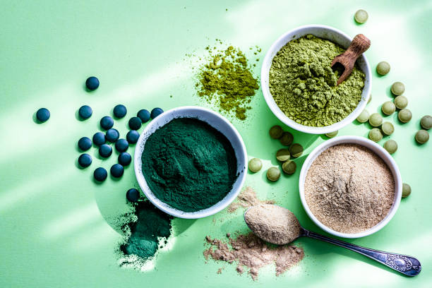 spirulina, maca und moringa pulver und pillen auf grünem hintergrund - superfood stock-fotos und bilder