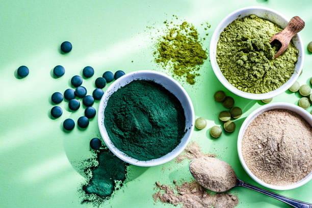 spirulina, maca und moringa pulver auf grünem hintergrund - vitamin pill nutritional supplement capsule antioxidant stock-fotos und bilder