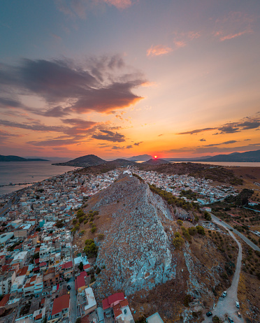 Aerial panoramic photo of the island of Salamis and the church of Prophet Elias over the rocky hill during sunset at summer