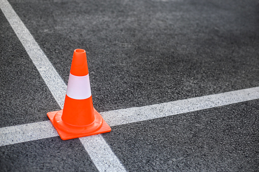 Driving obstacle course - asphalt, traffic cone and a car.