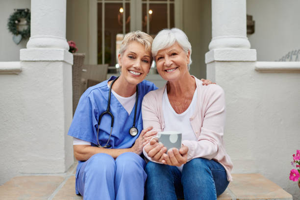 Shot of an elderly woman sitting on a porch outside with her nurse stock photo