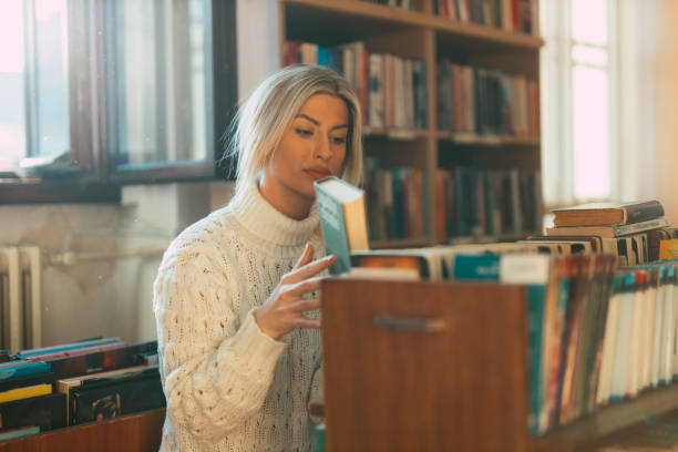 istock Woman looking for books to read in the library 1335867862