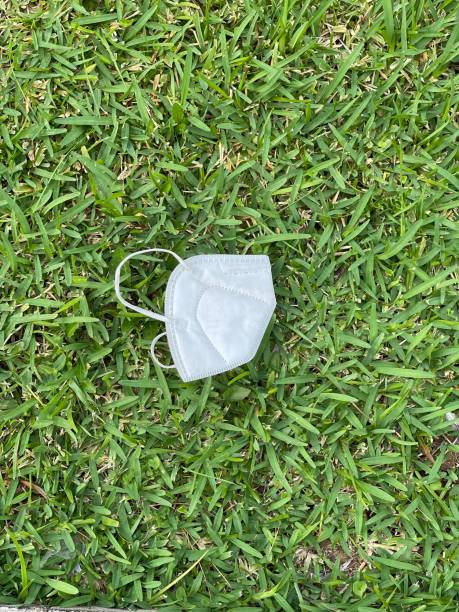 istock Covid mask worn on green grass background 1335867994