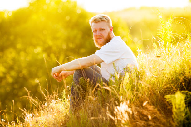 istock Bearded young man sitting on the grass on a summer day 1335868074
