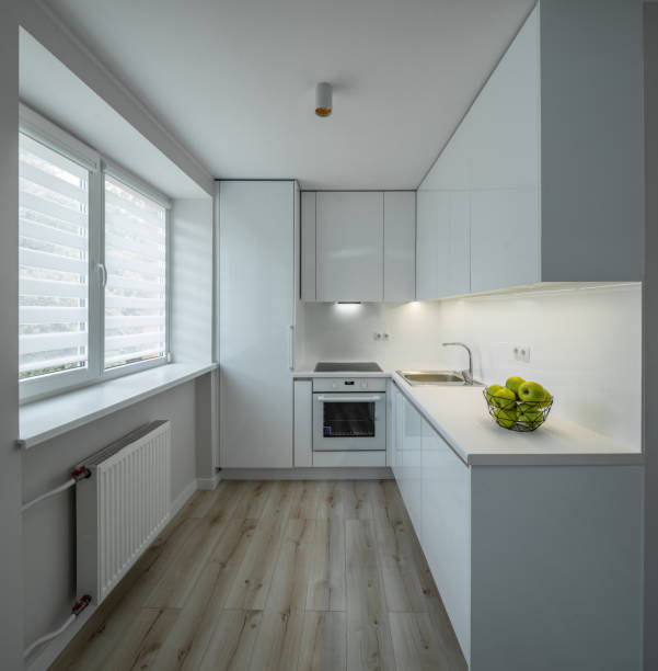 istock Bright interior of kitchen in luxury studio apartment. Parquet floor. White kitchen set with sink, oven and fridge. Green apples. 1335868203