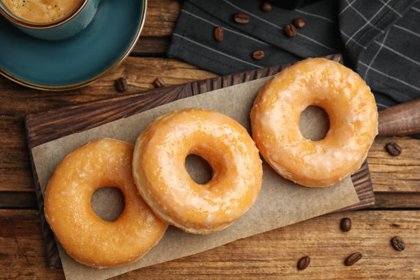 istock Delicious glazed donuts on wooden table, flat lay 1335868362