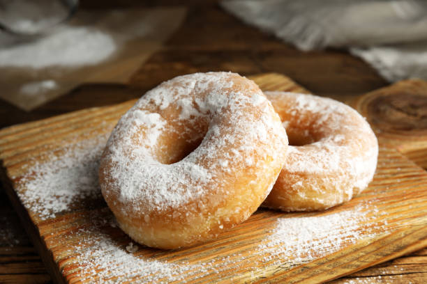 istock Delicious donuts with powdered sugar on wooden table 1335868392
