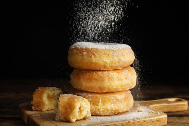 istock Delicious donuts with powdered sugar on wooden table 1335869082