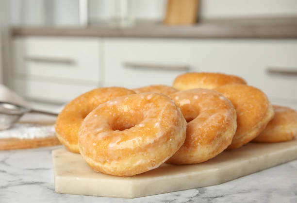 istock Delicious glazed donuts on marble table, closeup 1335869937