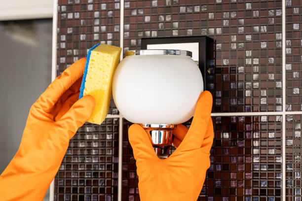 cleaning service concept. person dusting and washing wall light stock photo