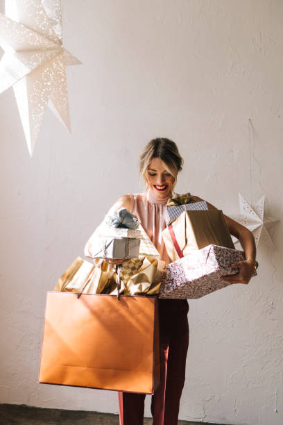 femme heureuse tenant des cadeaux de noël dans ses mains - women holding shopping bag living room photos et images de collection