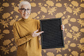 Senior woman showing blackboard with space for editing