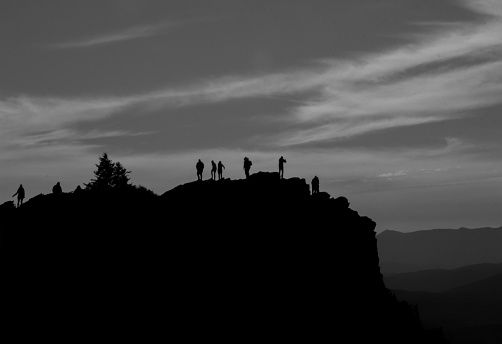 A group of tourists are silhouetted against the dusk sky at Grandfather Mountain State Park. They are taking in the beauty of the evening.